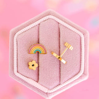 Pierced Co. Pastel Rainbows Earrings
Gold earrings with rainbow and flower designs in a pink hexagonal jewelry box on a pink background