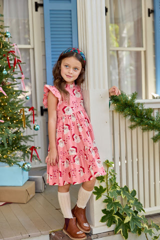Pink Chicken Girls Jennifer Dress - Pink Candy Cane Santa
Young girl in a pink dress standing on a porch decorated for Christmas.