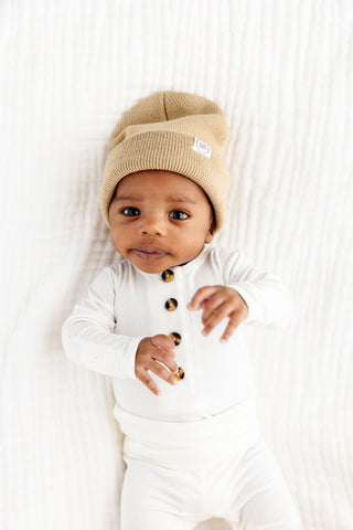 Lou Lou and Company Top and Bottoms - Finley
Baby wearing a beige knit hat and white outfit with brown buttons on a white background