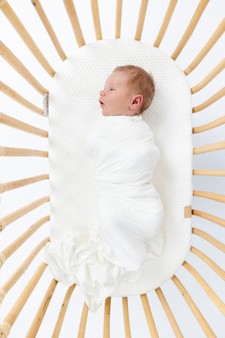 Lou Lou and Company Swaddle Blanket - Finley
Newborn baby wrapped in a white swaddle lying in a wooden crib.