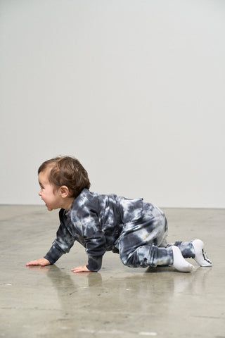 Little Bipsy Marble Pullover - Blue
Child in a tie-dye outfit crawling on a reflective floor.