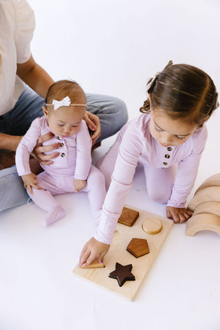 Lou Lou and Company Top and Bottoms - Isabelle
Two children playing with a wooden shape puzzle on a white floor.