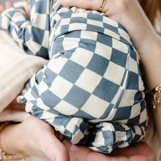 Lou Lou and Company Top and Bottoms - Miles
Close-up of a baby in blue and white checkered pants held by a person.