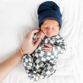 Lou Lou and Company Top and Bottoms - Miles
Newborn baby wrapped in a blue and white checkered outfit with a matching hat, held by a person's hand on a white background.