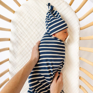 Lou Lou and Company Ribbed Swaddle Blanket - Jack
Baby swaddled in a blue and white striped blanket with matching hat, lying in a wooden crib.