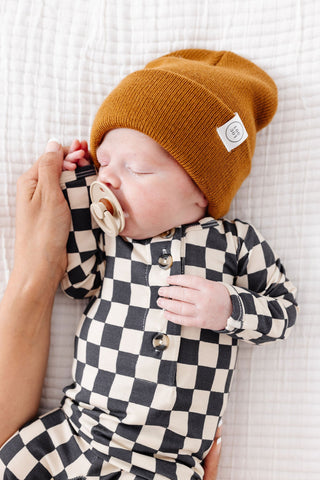 Lou Lou and Company Top and Bottoms - Gibson
Newborn baby wearing a checkered outfit and mustard-colored knit hat on a white textured surface.