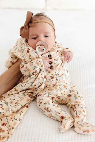 Lou Lou and Company Top and Bottoms - Rachel
Baby in a floral onesie with a pacifier and headband on a white background