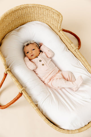 Lou Lou and Company Top and Bottoms - Sophie
Newborn baby in a pink outfit lying in a wicker crib with white bedding.