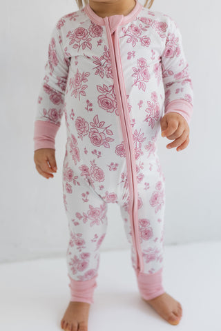 In My Jammers Blush Garden Zipper Romper
Child wearing a pink floral onesie on a white background