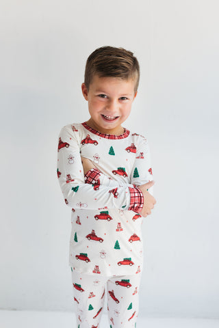 In My Jammers Red Holly Jolly Cruisers Two Piece Set
Child wearing Christmas-themed pajamas with red and green designs on a white background