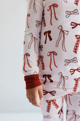 In My Jammers Merry Little Bows Two Piece Set
Close-up of a person wearing pajamas with bow pattern on a plain background