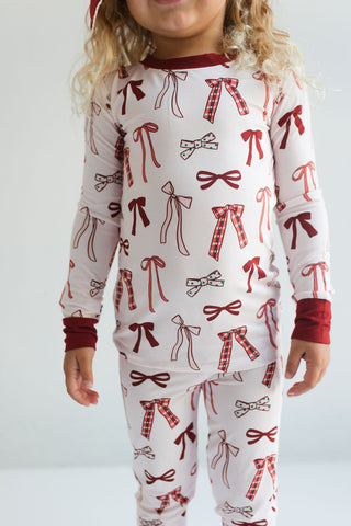 In My Jammers Merry Little Bows Two Piece Set
Child wearing a pajama set with red and brown bow pattern on a white background