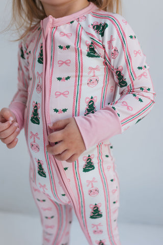 In My Jammers Pinkmas Zipper Romper
Child wearing a pink pajama set with festive patterns on a white background