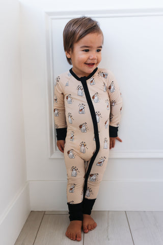 In My Jammers DJ BooMBox Zipper Romper Child wearing a beige onesie with black zipper and animal print against a white wall.