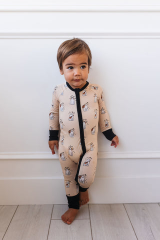 In My Jammers DJ BooMBox Zipper Romper Child wearing a beige onesie with black zipper and animal print against a white wall.