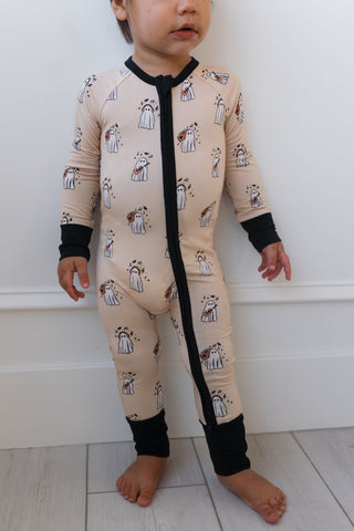 In My Jammers DJ BooMBox Zipper Romper Child wearing a beige onesie with black zipper and panda pattern against a white wall.