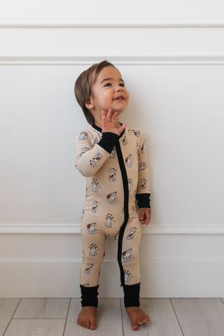 In My Jammers DJ BooMBox Zipper Romper Child wearing a patterned onesie standing against a white wall.