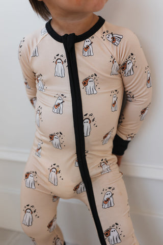 In My Jammers DJ BooMBox Zipper Romper Child wearing a beige onesie with dog print and black tie, standing against a white wall.