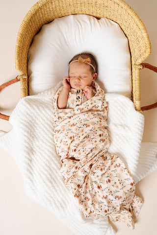 Lou Lou and Company Swaddle Blanket - Rachel
Newborn baby swaddled in a floral blanket lying in a wooden crib.