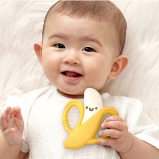 Itzy Ritzy Chew Crew® - Banana Baby holding a yellow teething toy with a smile on a white background