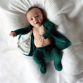 Bonsie Footie - Ever Babe
Baby wearing a green outfit on a textured white blanket