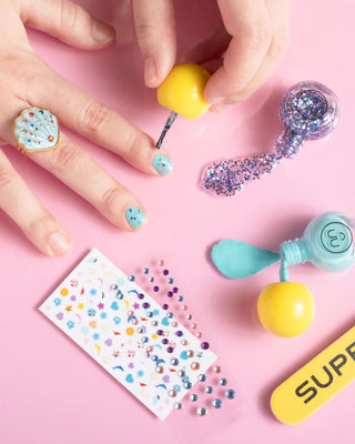 Super Smalls Paint It Mermaid Mini Nail Kit Nail art station with nail polish, stickers, and decorative beads on a pink background