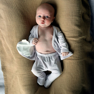 Bonsie Footie - Hush Sky
Baby in white outfit lying on a textured brown surface