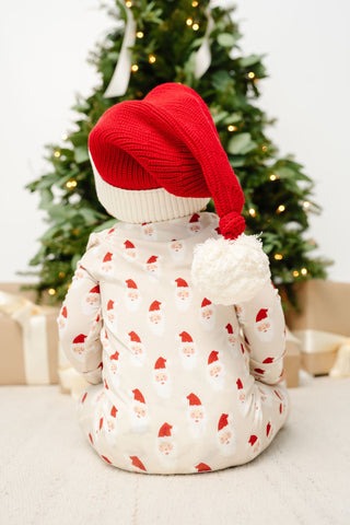 Lou Lou and Company Santa Beanie
Child wearing a red hat and patterned outfit in front of a decorated Christmas tree.