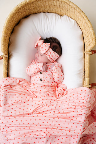 Lou Lou and Company Headband - Miley
Baby in a crib wearing a pink outfit with a bow, surrounded by pink and white bedding.