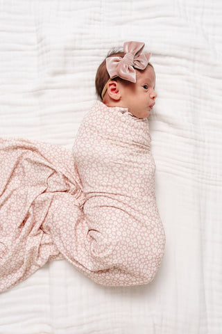 Lou Lou and Company Swaddle Blanket - Flora
Newborn baby wrapped in a pink swaddle with a matching bow on a white background