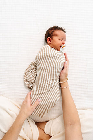 Lou Lou and Company Ribbed Swaddle Blanket - Indy
Newborn baby swaddled in a striped blanket held by a person on a white background