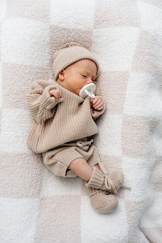 Lou Lou and Company Knit Booties - Tan
Newborn baby in beige knit outfit lying on a soft blanket
