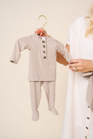 Lou Lou and Company Top and Bottoms - Banks
Baby outfit with striped shirt and pants on a hanger, held by a person against a neutral background