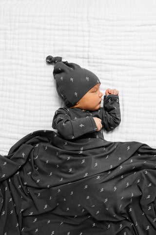 Lou Lou and Company Top and Bottoms - Everett
Newborn baby wrapped in a black blanket with a matching hat against a white textured background