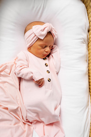 Lou Lou and Company Headband - Sophie
Newborn baby in a pink outfit with a bow headband, lying on a white pillow.