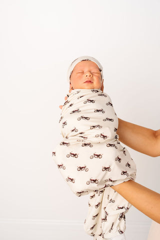 Lou Lou and Company Swaddle Blanket - Cruz
Newborn baby wrapped in a white blanket with brown patterns on a plain background