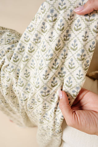 Lou Lou and Company Swaddle Blanket - Etta
Close-up of hands holding a folded fabric with floral pattern on a neutral background