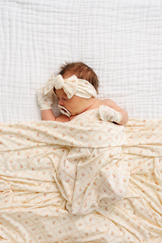 Lou Lou and Company Swaddle Blanket - Annie
Lou Lou and Company Headband - Annie 
Newborn baby wrapped in a white blanket with a white headband on a white background