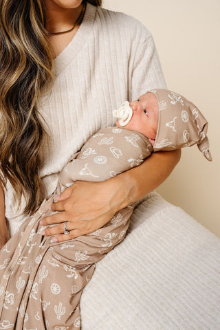 Lou Lou and Company Swaddle Blanket - Wyatt
Woman holding a baby wrapped in a patterned blanket and wearing a matching hat.