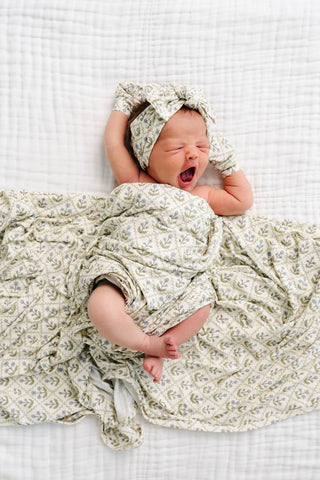 Lou Lou and Company Swaddle Blanket - Etta
Newborn baby wrapped in a floral blanket and headband on a white checkered background