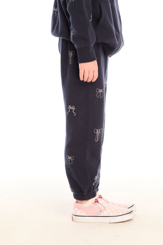 Chaser Tossed Glitter Bows Pants
Person wearing navy jogger pants with white graphics on a white background