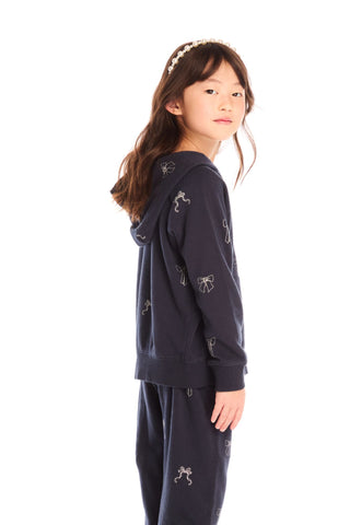 Chaser Tossed Glitter Bows Zip Up Hoodie
Young girl wearing a navy blue hoodie and pants with small designs on a white background