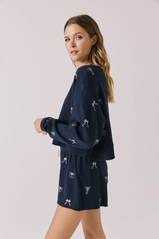 Chaser Tossed Bows Women's Long Sleeve
Woman wearing a navy blue dress with white patterns on a plain background