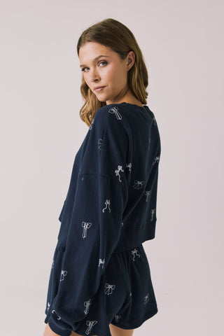 Chaser Tossed Bows Women's Long Sleeve
Woman wearing a navy blue outfit with small white patterns on a plain background