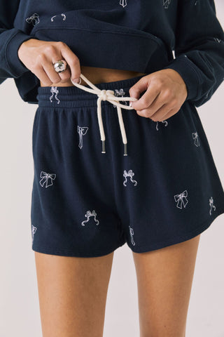 Chaser Tossed Bows Navy Blue Shorts
Navy shorts with white patterns worn by a person on a plain background