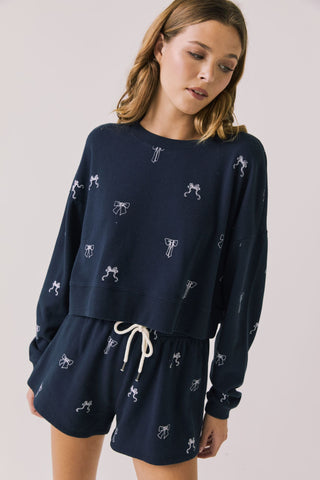 Chaser Tossed Bows Women's Long Sleeve
Woman wearing a navy blue outfit with white patterns on a plain background