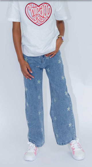 Lola and The Boys Crystal Stars Jeans Person wearing a white t-shirt with a red heart design and blue jeans with star patterns on a plain background