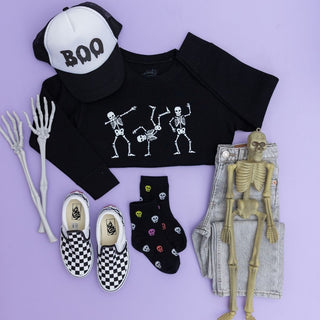 Sweet Wink Boo Drip Halloween Trucker Hat - Black/White Halloween-themed clothing and accessories including a black crop top with skeleton design, checkered shoes, and a cap with 'BOO' text on a purple background.