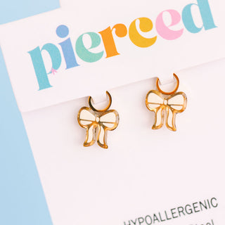 Pierced Co White Bows  Girly Things Charms Gold bow-shaped earrings on a 'pierced' branded card with a blue background