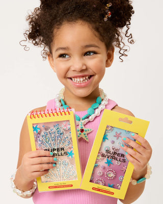 Super Smalls Under the Sea Gemify™ Sticker Booklet Child holding two packages of 'Super Smalls' jewelry with a plain background